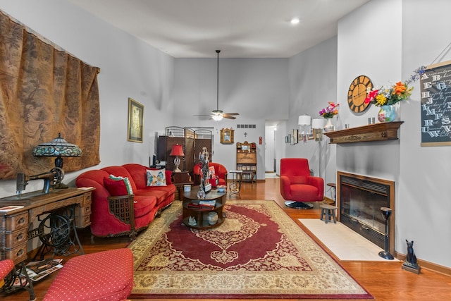 26901 Ann Arbor Trl, Dearborn Heights, MI 48127 - living room featuring wood finished floors, a fireplace with flush hearth, a ceiling fan, baseboards, and a high ceiling