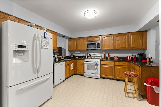 26901 Ann Arbor Trl, Dearborn Heights, MI 48127 - kitchen featuring white appliances, a sink, brown cabinetry, dark countertops, and light flooring