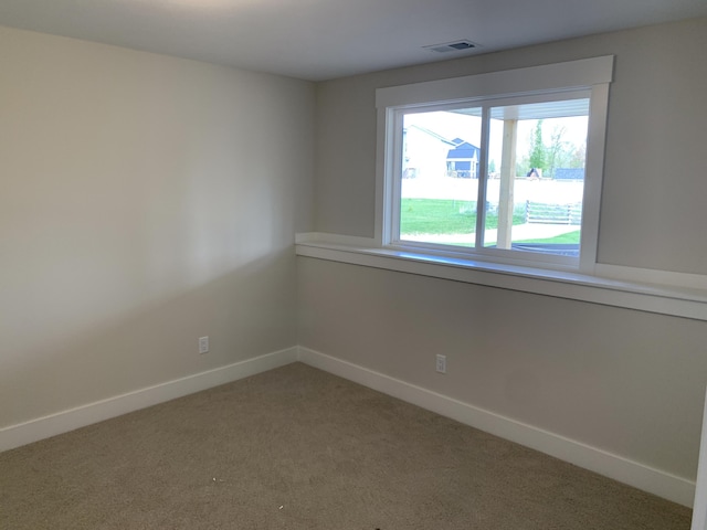 unfurnished room featuring baseboards, visible vents, and light carpet