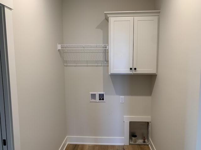 laundry area featuring baseboards, washer hookup, wood finished floors, and cabinet space
