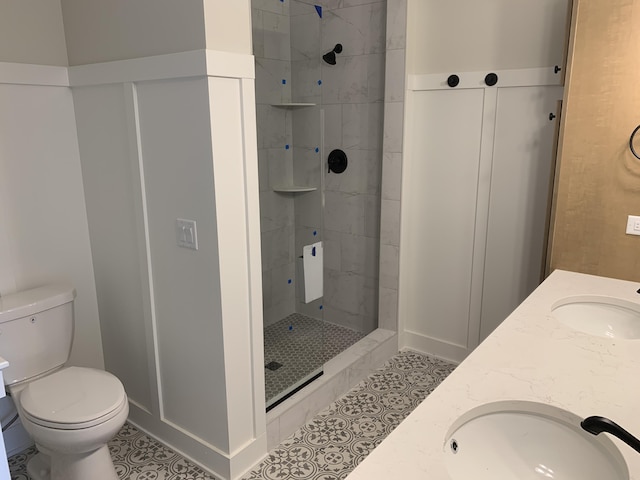 bathroom featuring vanity, baseboards, a tile shower, and toilet