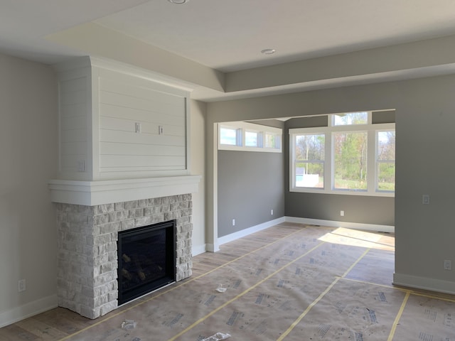 unfurnished living room with baseboards, wood finished floors, and a fireplace