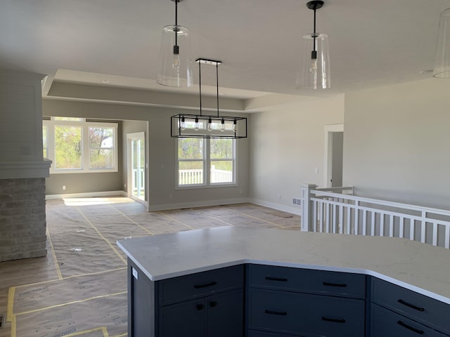 kitchen with baseboards, light stone countertops, decorative light fixtures, and open floor plan