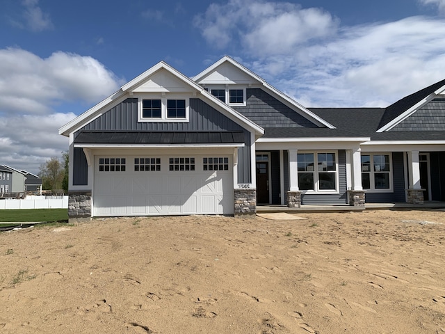 craftsman inspired home with fence, a shingled roof, stone siding, board and batten siding, and driveway