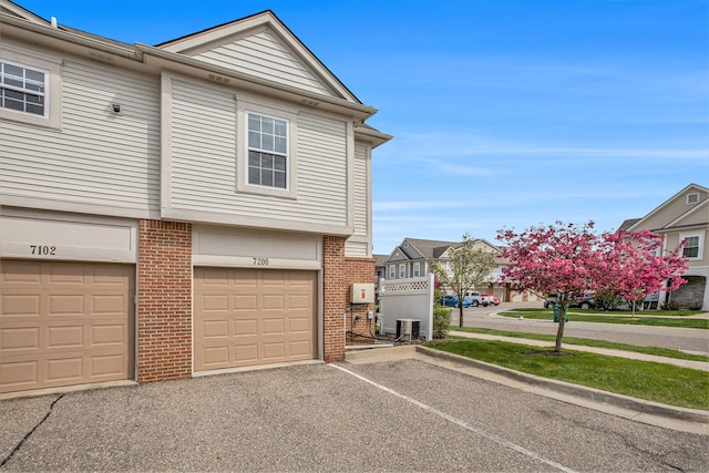 7200 Addington Dr, Commerce Twp, MI 48390 - view of side of property featuring brick siding, a garage, aphalt driveway, and central AC
