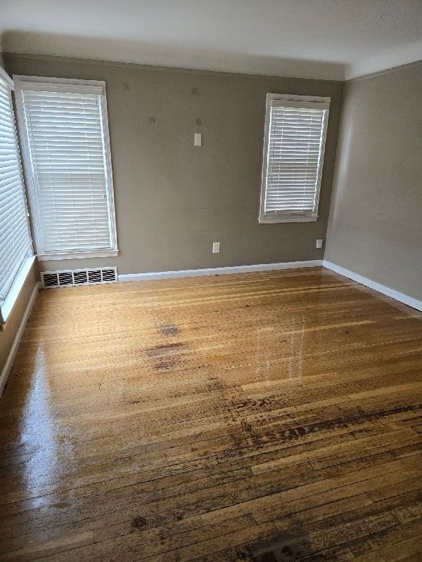 spare room featuring baseboards, visible vents, and wood finished floors