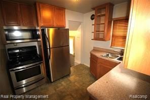 kitchen with a sink, light countertops, stainless steel appliances, and brown cabinets