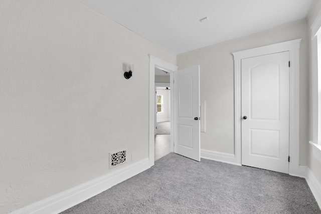 unfurnished bedroom featuring carpet floors, crown molding, and baseboards