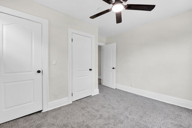 unfurnished bedroom with carpet floors, crown molding, baseboards, and a ceiling fan