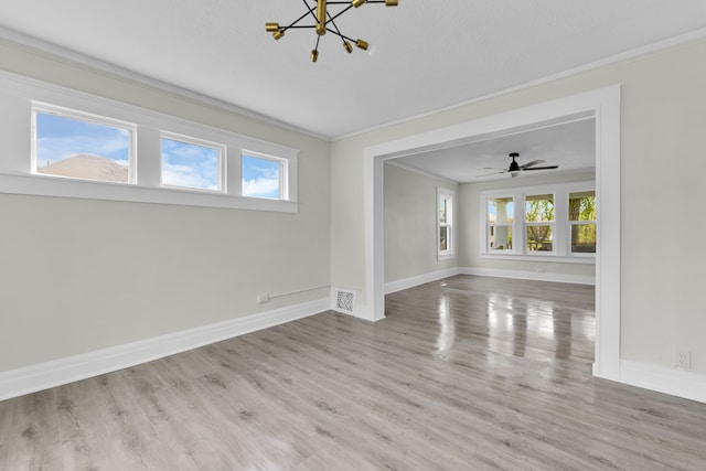 spare room featuring a chandelier, ornamental molding, plenty of natural light, wood finished floors, and baseboards