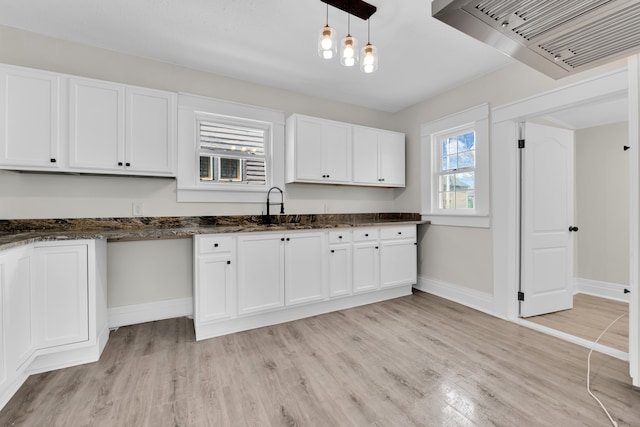 kitchen featuring custom range hood, light wood-style floors, white cabinetry, and baseboards