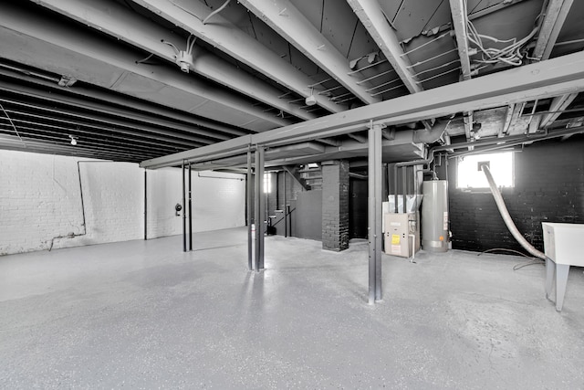 basement featuring water heater and brick wall