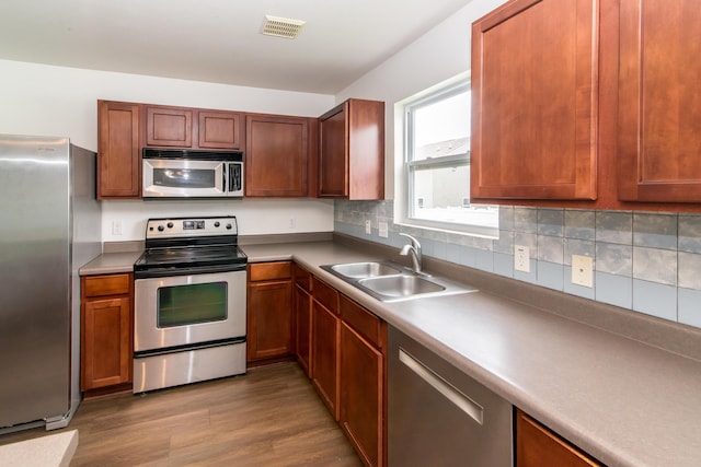 kitchen featuring dark wood-style flooring, visible vents, appliances with stainless steel finishes, tasteful backsplash, and a sink