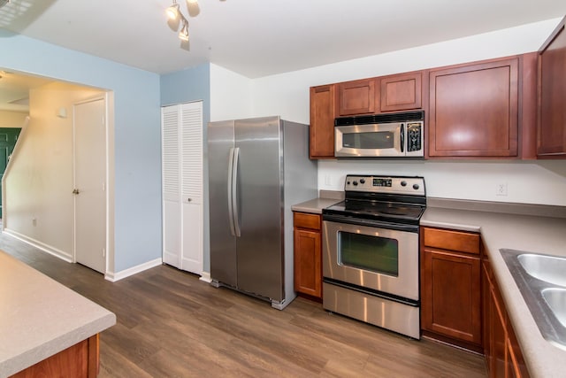 kitchen with brown cabinets, stainless steel appliances, baseboards, and dark wood finished floors