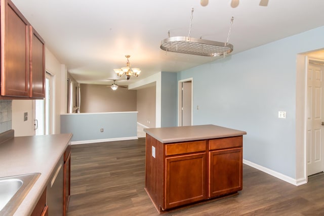 kitchen featuring brown cabinetry, baseboards, dark wood-type flooring, a sink, and ceiling fan with notable chandelier