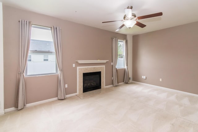 unfurnished living room featuring baseboards, carpet flooring, ceiling fan, and a premium fireplace