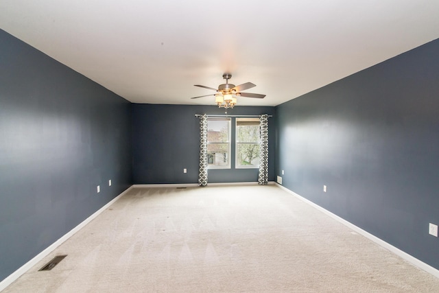 empty room featuring baseboards, light carpet, a ceiling fan, and visible vents
