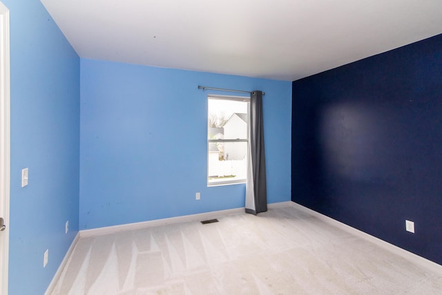 carpeted spare room featuring baseboards and visible vents