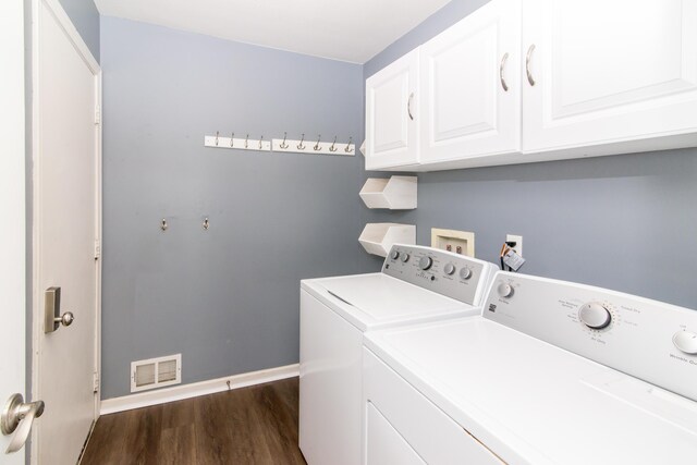 clothes washing area featuring visible vents, baseboards, dark wood-type flooring, washer and clothes dryer, and cabinet space