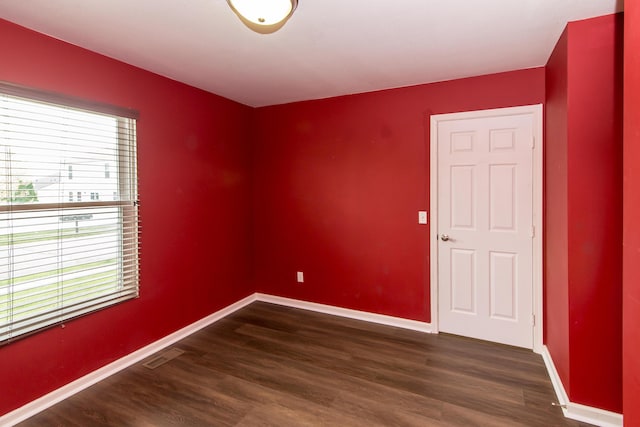 unfurnished room with baseboards, dark wood finished floors, and visible vents
