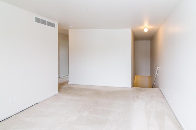 empty room featuring visible vents, baseboards, and light colored carpet