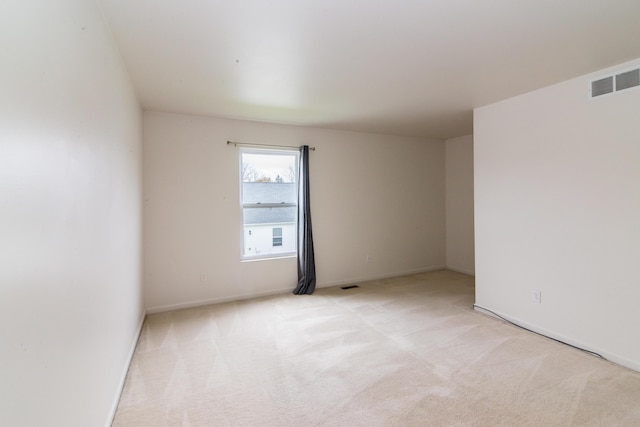 spare room with baseboards, visible vents, and light carpet