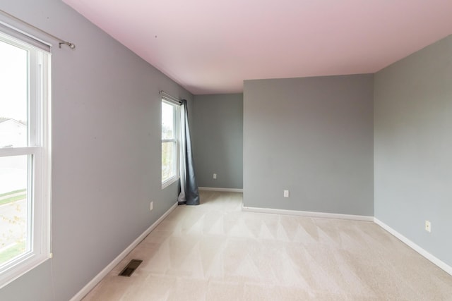 spare room with baseboards, visible vents, and light carpet