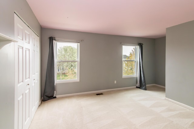 unfurnished bedroom with visible vents, baseboards, light carpet, and multiple windows