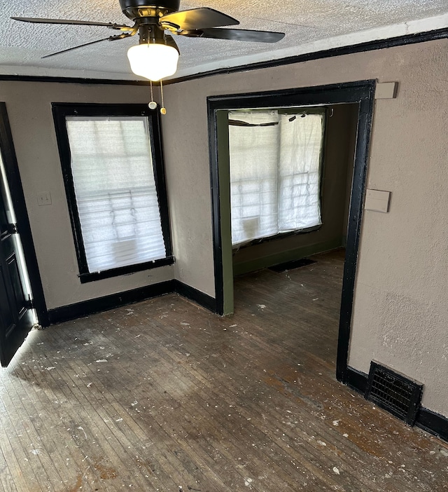 interior space featuring a textured ceiling, a ceiling fan, hardwood / wood-style floors, and a textured wall