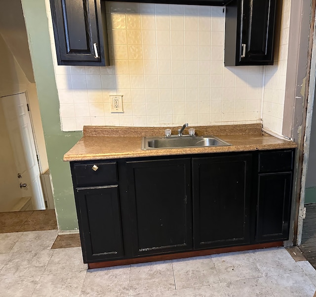 kitchen with dark cabinets, tasteful backsplash, and a sink