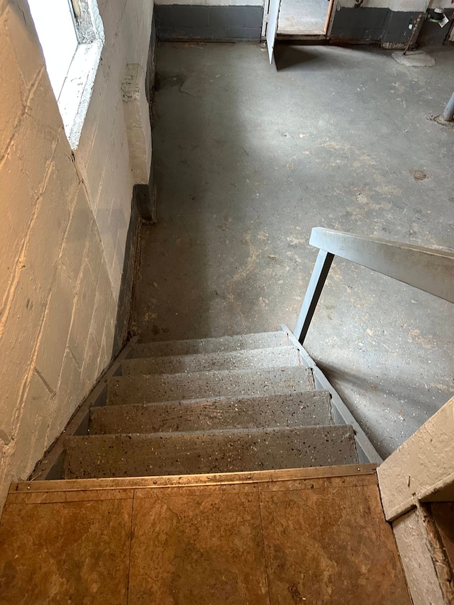 staircase featuring concrete block wall