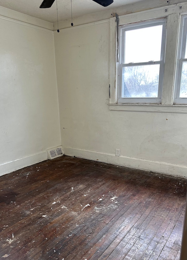 spare room featuring ceiling fan, wood-type flooring, baseboards, and visible vents