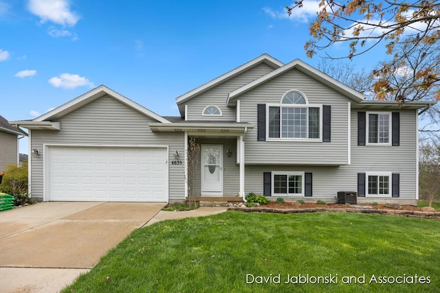 tri-level home with central AC unit, an attached garage, driveway, and a front yard