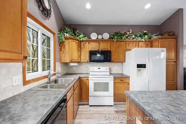 kitchen with a sink, light wood-style flooring, backsplash, and black appliances