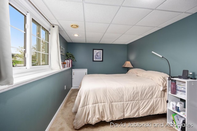 carpeted bedroom featuring baseboards and a paneled ceiling