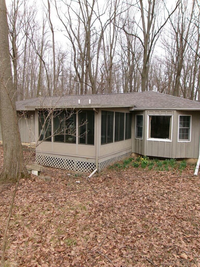 rear view of property with a sunroom and roof with shingles