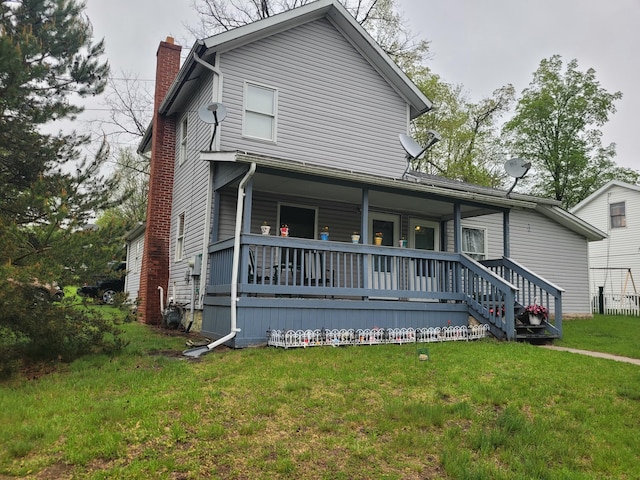 traditional-style home with covered porch, a chimney, and a front yard