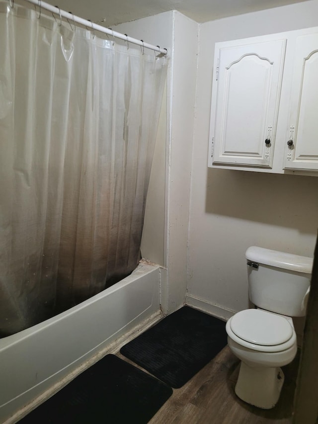 bathroom with toilet, wood finished floors, and shower / tub combo with curtain