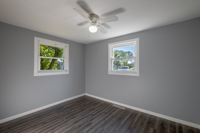 empty room with baseboards, dark wood-style floors, and a ceiling fan