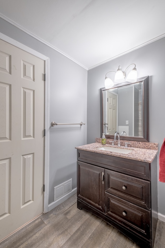 bathroom with wood finished floors, vanity, ornamental molding, and baseboards