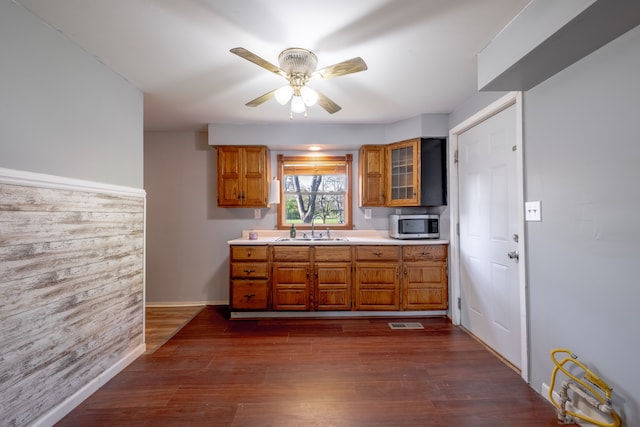 kitchen with stainless steel microwave, a sink, brown cabinetry, and light countertops