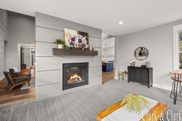 living area with a glass covered fireplace, baseboards, and recessed lighting
