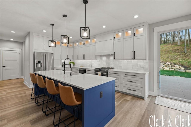 kitchen featuring a kitchen breakfast bar, light wood-style flooring, stainless steel appliances, baseboards, and tasteful backsplash