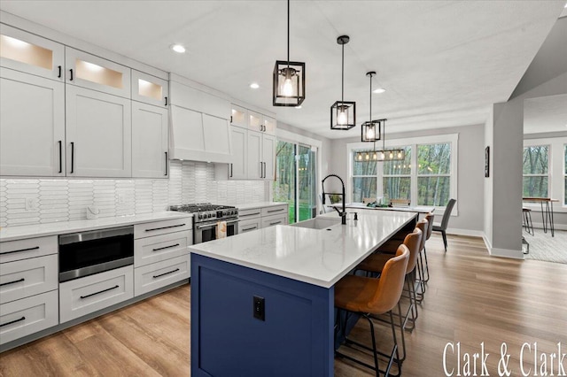 kitchen with baseboards, recessed lighting, tasteful backsplash, a sink, and appliances with stainless steel finishes