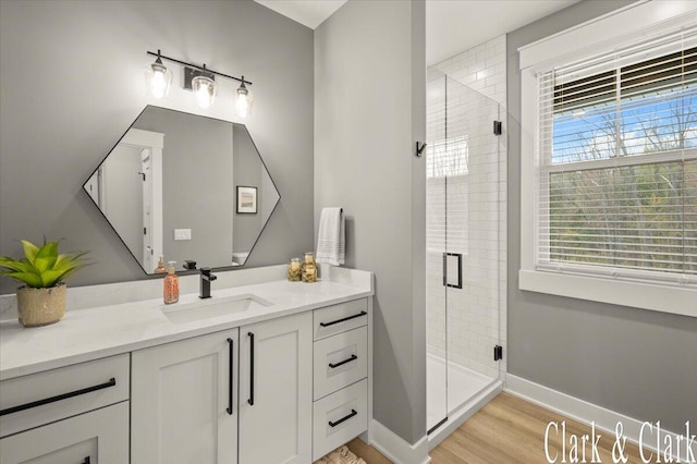 full bathroom with vanity, baseboards, wood finished floors, and a shower stall