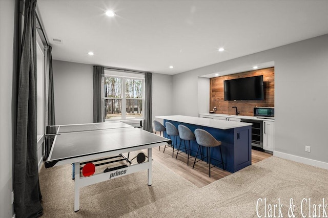 recreation room featuring baseboards, indoor wet bar, beverage cooler, recessed lighting, and light wood-style flooring