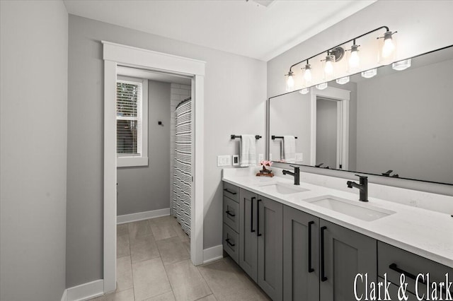 bathroom with a sink, baseboards, tile patterned floors, and double vanity