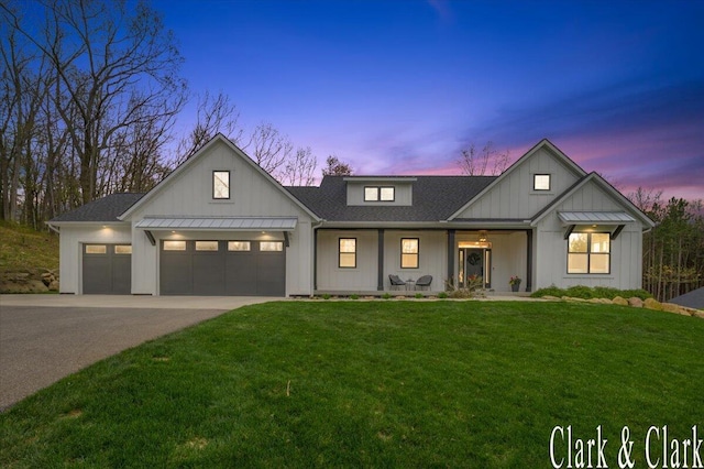 modern farmhouse with board and batten siding, a porch, driveway, a yard, and an attached garage