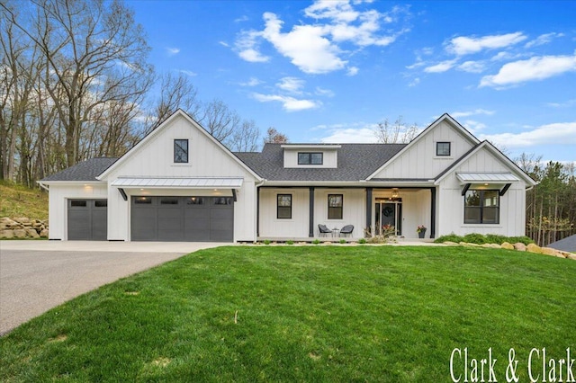 modern farmhouse featuring board and batten siding, an attached garage, driveway, and a front yard