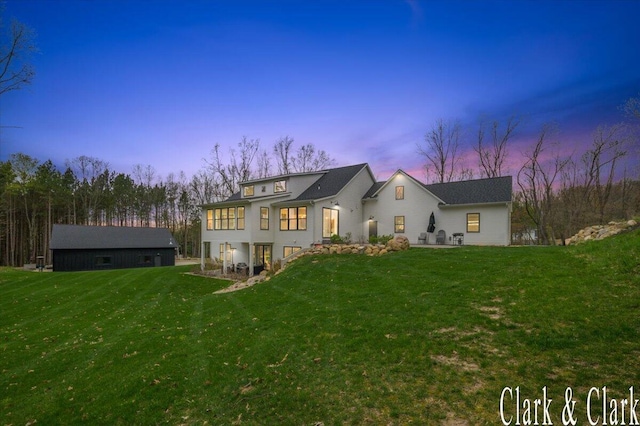 back of property at dusk featuring a yard